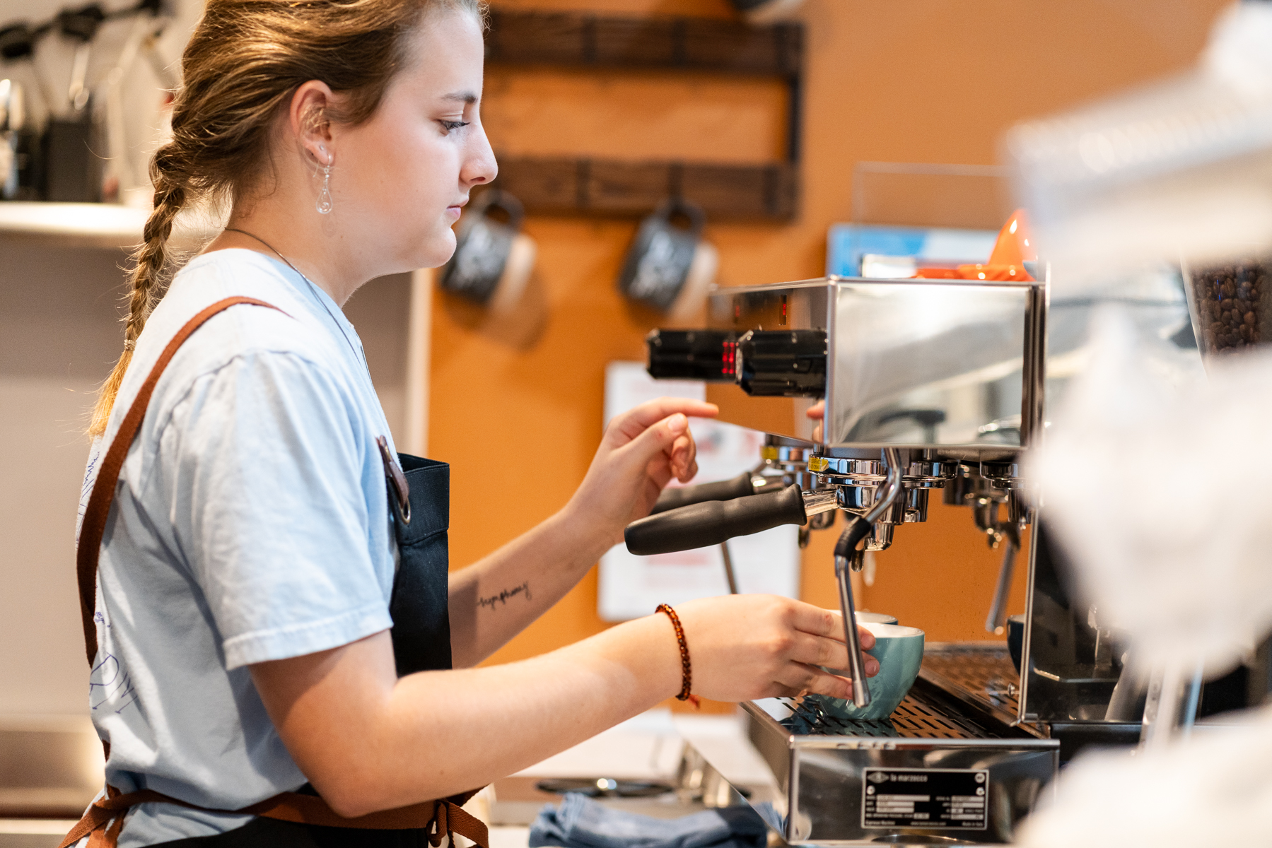 A barista steaming milk at the La Marzocco espresso machine behind the bar during the Bouldering Baristas latte art throwdown at APEX Coffee Bar